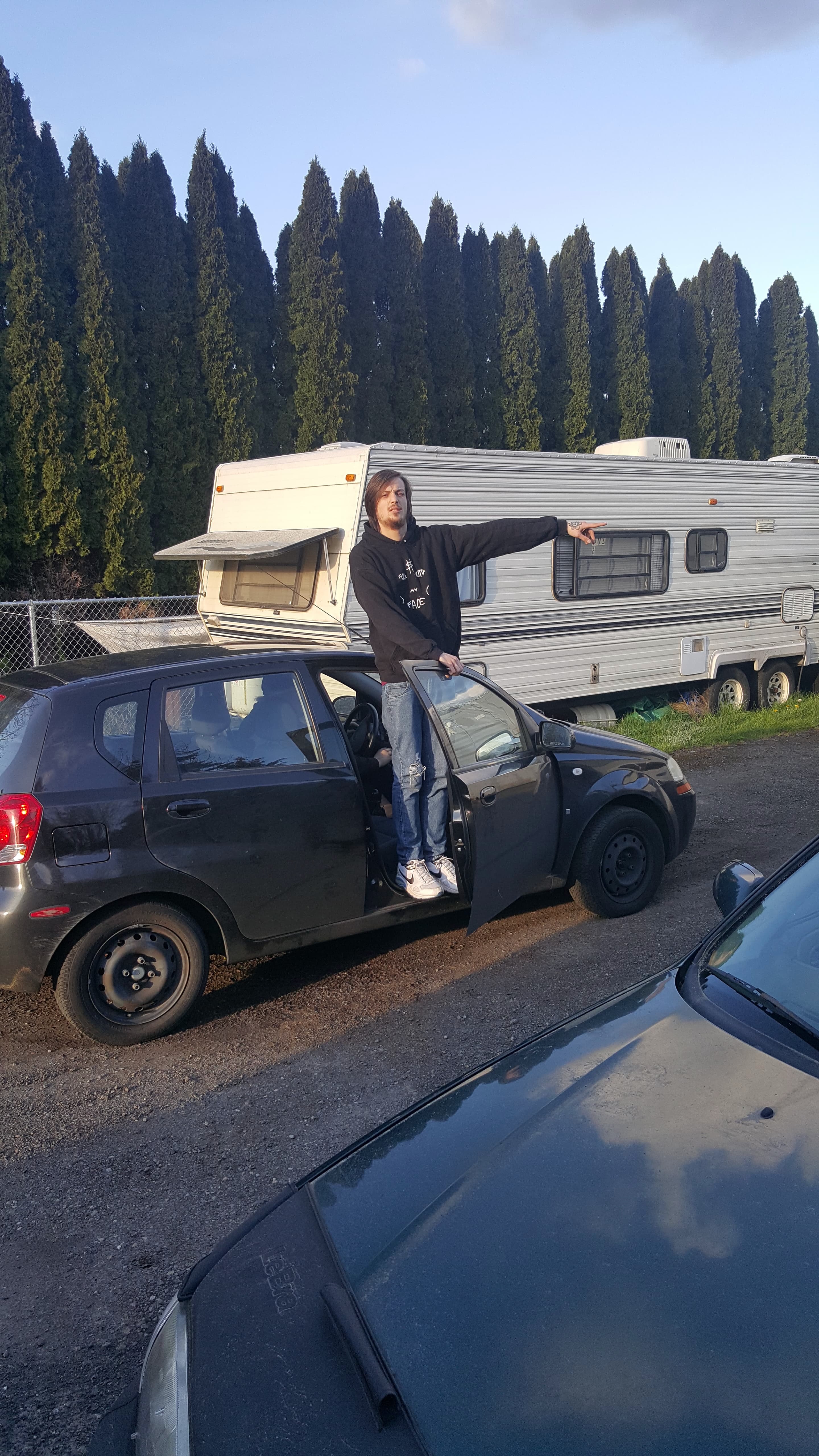 A man standing in the partially-open door of a car.