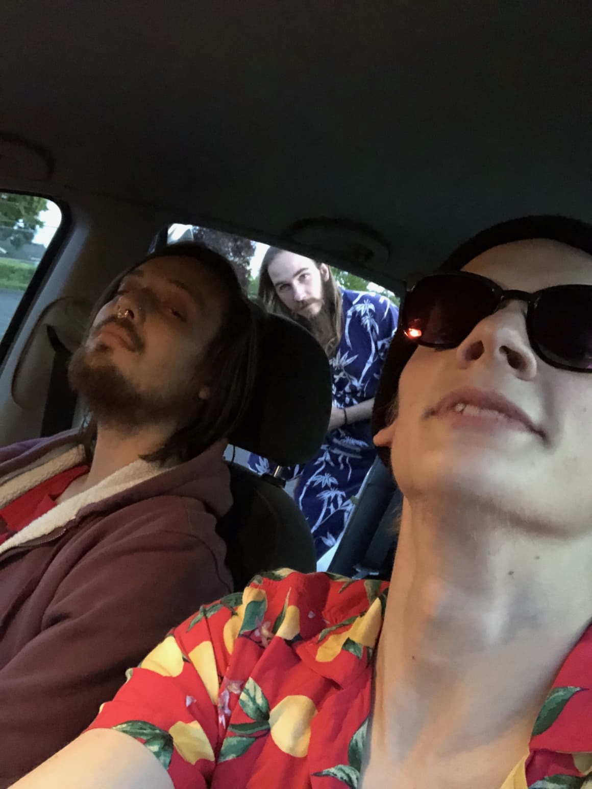 Two men sitting in a car, with a third about to enter.